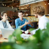 Kolleg:innen sitzen gemeinsam am Tisch und arbeiten