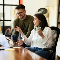 Kolleg*innen besprechen etwas an Laptops